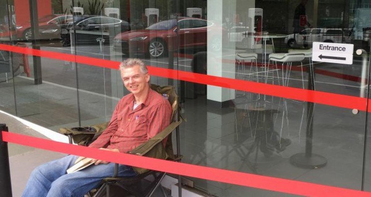 Un Australien fait le pied de grue devant un Tesla Store